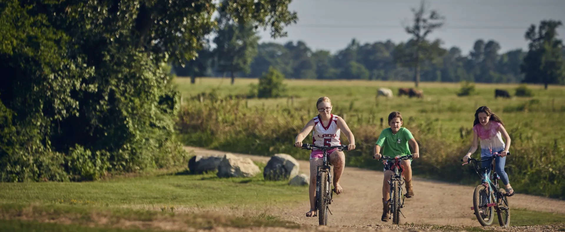 Three white kids biking in a rural area