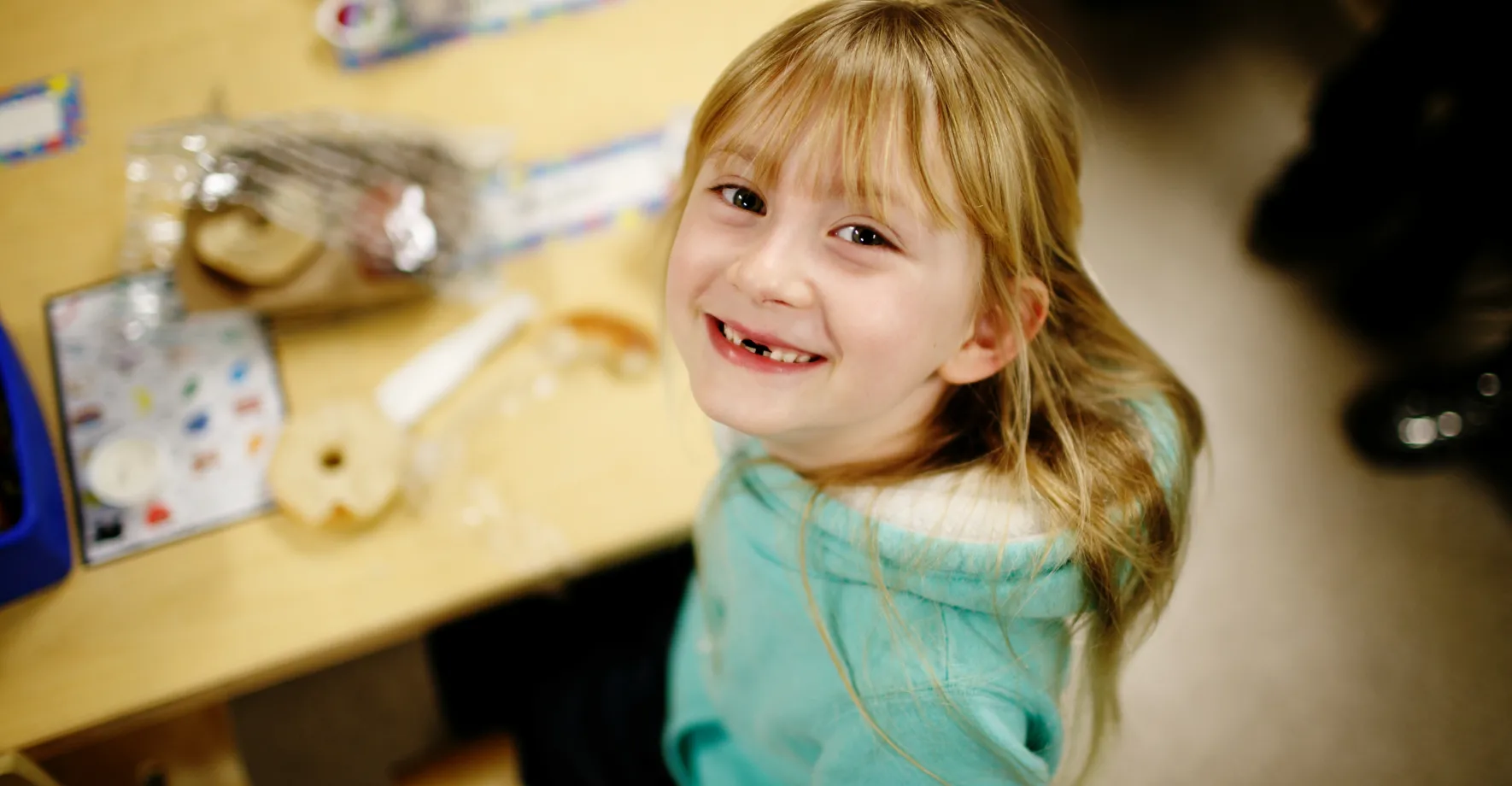 Little girl beaming and eating school breakfast