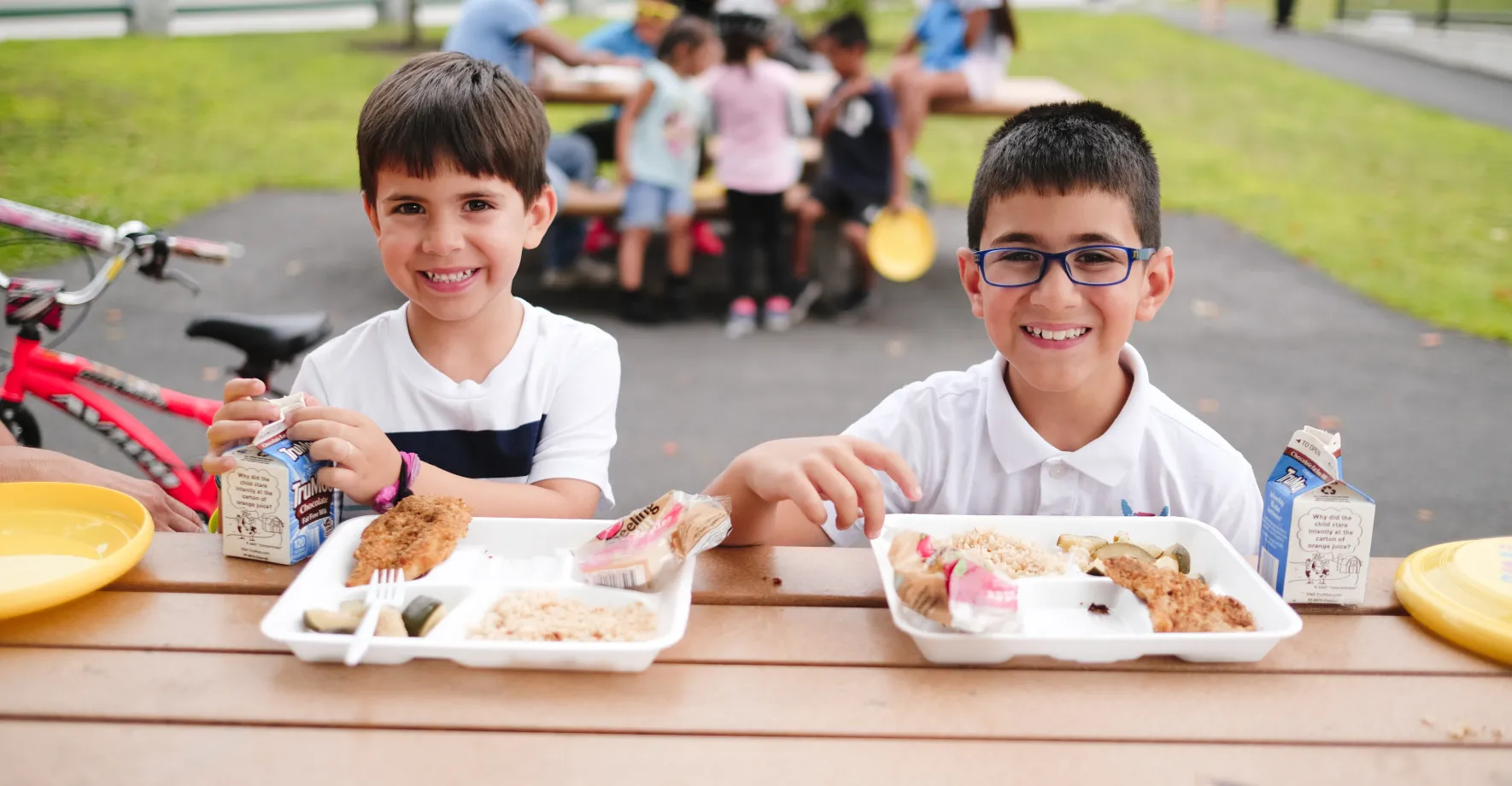 two kids eating a lunch outside