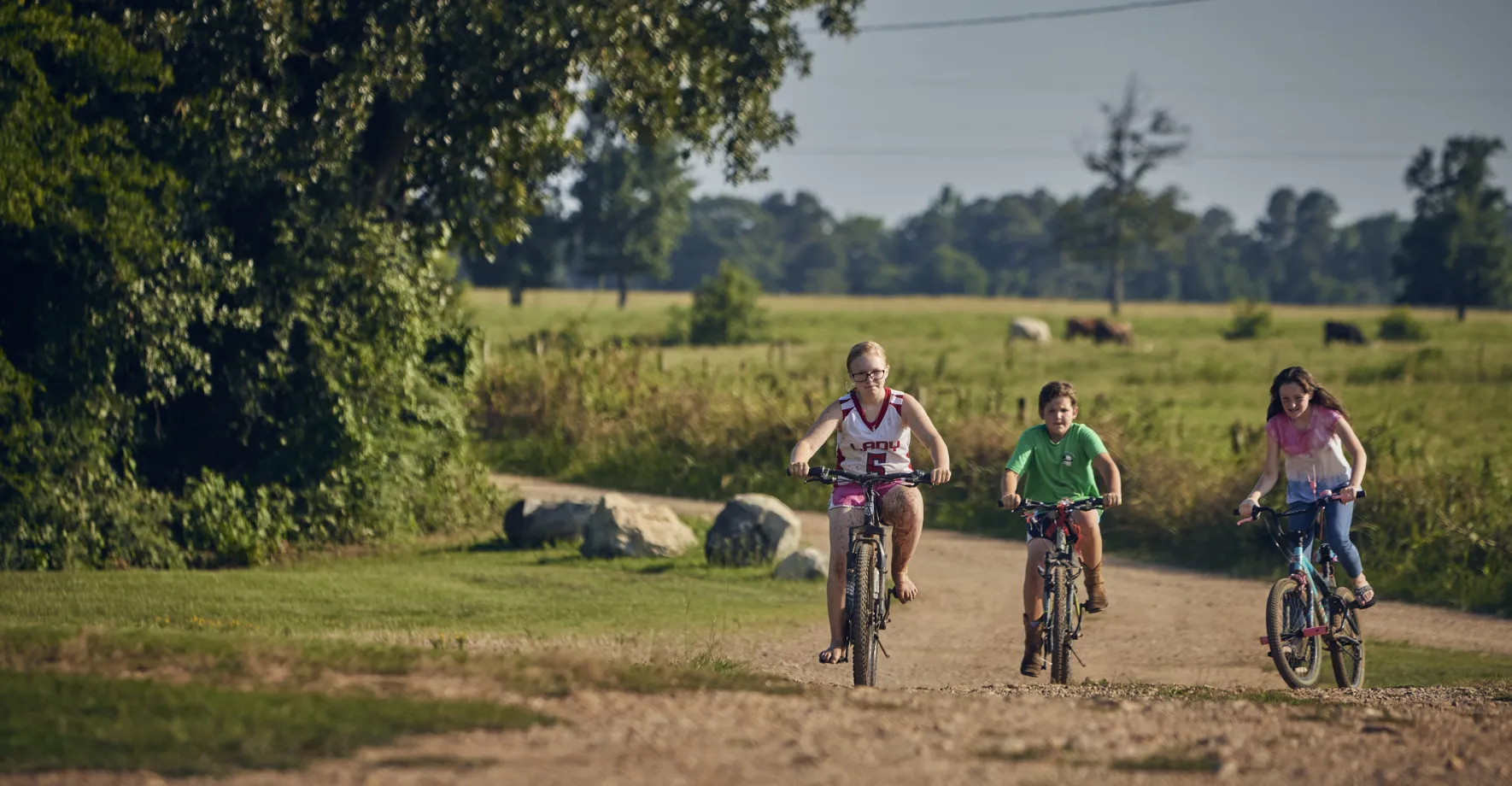 Three white kids biking in a rural area