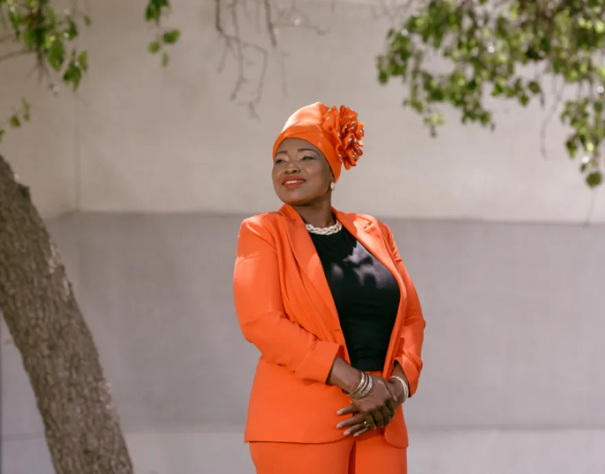 Fausat Rahman-Davies in an orange suit and head wrap.