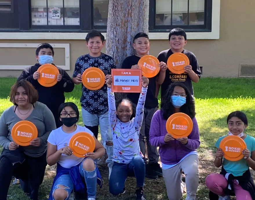 Kids holding No Kid Hungry frisbees