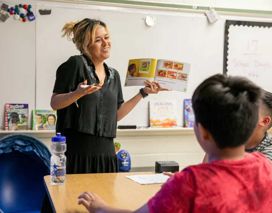 Teacher talking to two students with book in hand