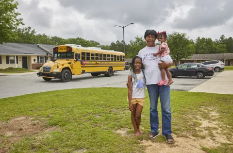 Family standing in front of school bus
