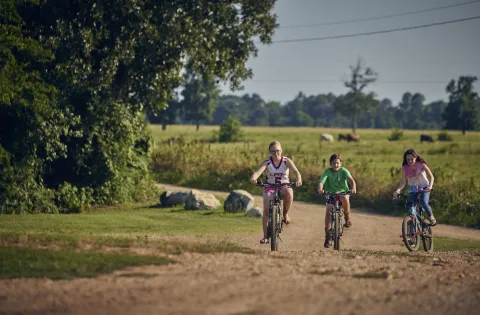 Three white kids biking in a rural area 1