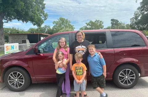 White family in front of red car (1 mom 3 kids)